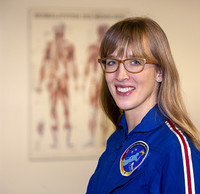 Portrait Dr. Insa Thiele-Eich in blauer Uniform vor Plakat mit anatomischer Zeichnung Mensch